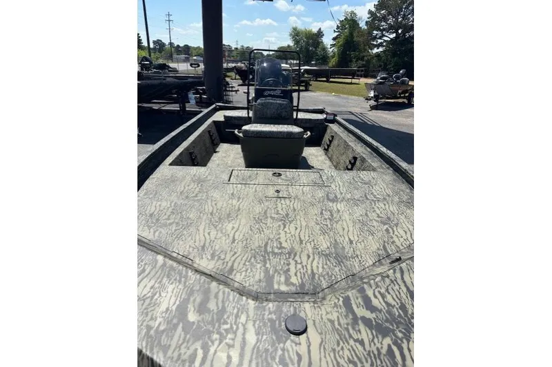 Slide: The Image of 2026 Tracker Grizzly 1860 CC boat with camouflage design, parked outdoors under clear skies. - 7