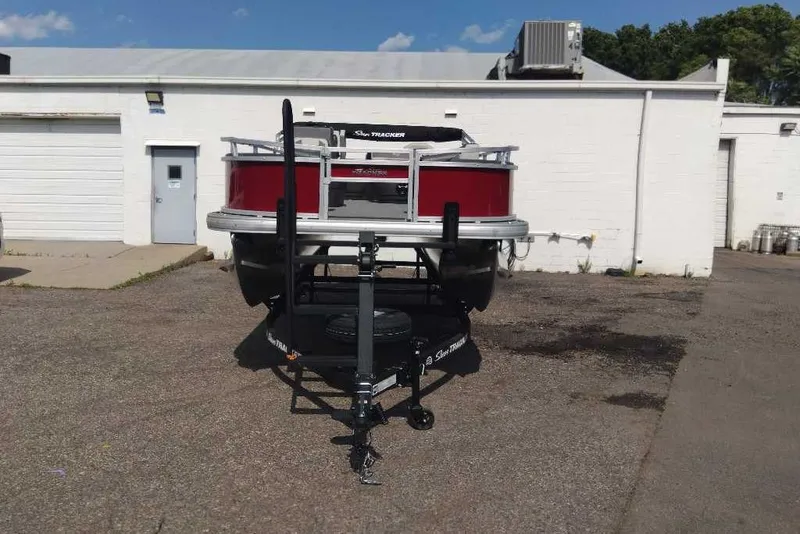 Slide: The Image of 2026 Sun Tracker Bass Buggy 18 DLX pontoon boat on trailer in parking lot. - 4