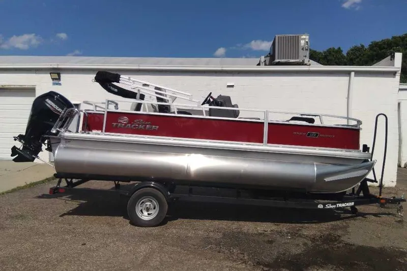 Slide: The Image of 2026 Sun Tracker Bass Buggy 18 DLX pontoon boat on trailer, parked outdoors. - 5