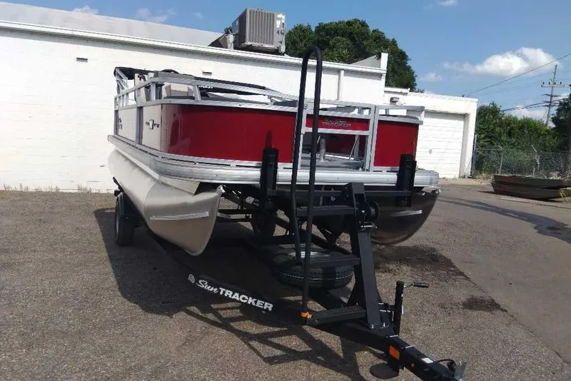 Slide: The Image of 2026 Sun Tracker Bass Buggy 18 DLX pontoon boat on trailer, parked outdoors. - 2