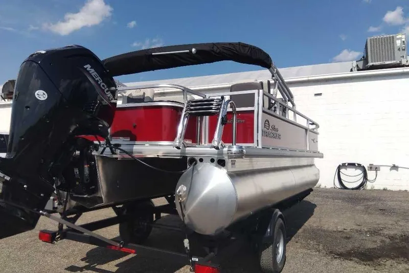Slide: The Image of 2026 Sun Tracker Bass Buggy 18 DLX pontoon boat with Mercury engine, parked outdoors. - 8