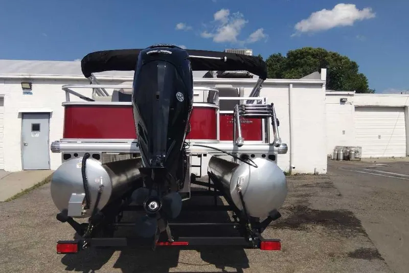 Slide: The Image of 2026 Sun Tracker Bass Buggy 18 DLX pontoon boat, rear view with motor, parked outdoors. - 9