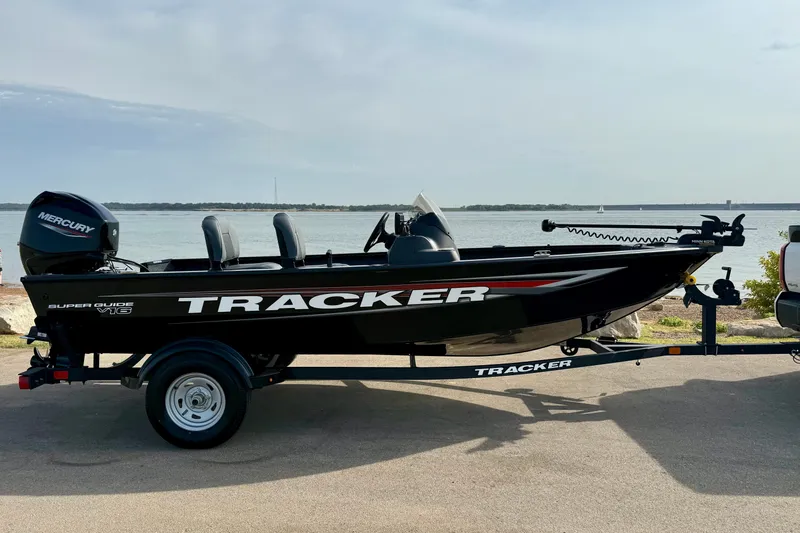 The Image of 2026 Tracker Super Guide V-16 SC boat on trailer by a lake. - 0