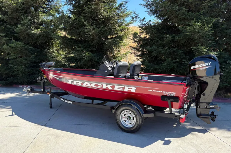 Slide: The Image of 2026 Tracker Super Guide V-16 SC boat with Mercury engine, parked outdoors. - 8