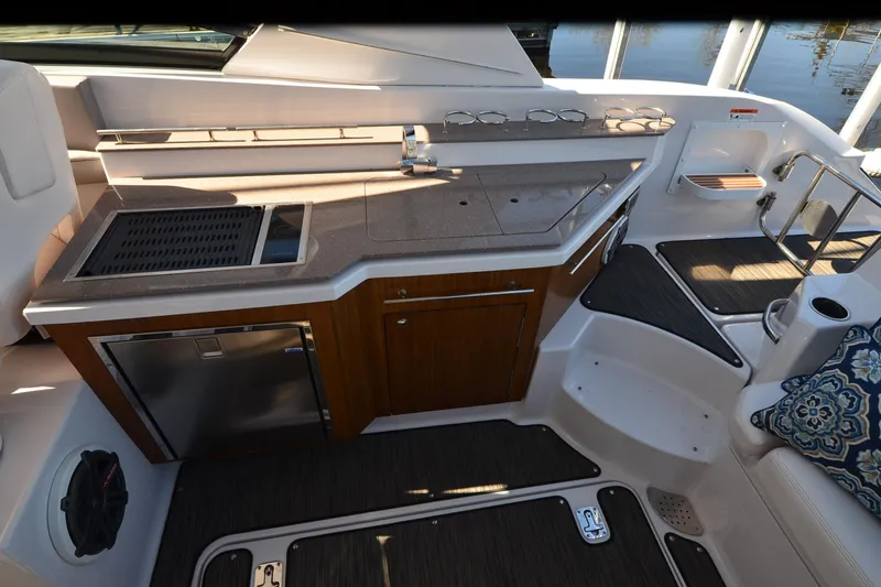 Slide: The Image of 2018 Four Winns H350 boat interior with kitchenette, featuring sink, grill, and seating area. - 17