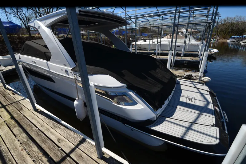 Slide: The Image of 2018 Four Winns H350 boat docked with black cover, in a marina setting. - 26