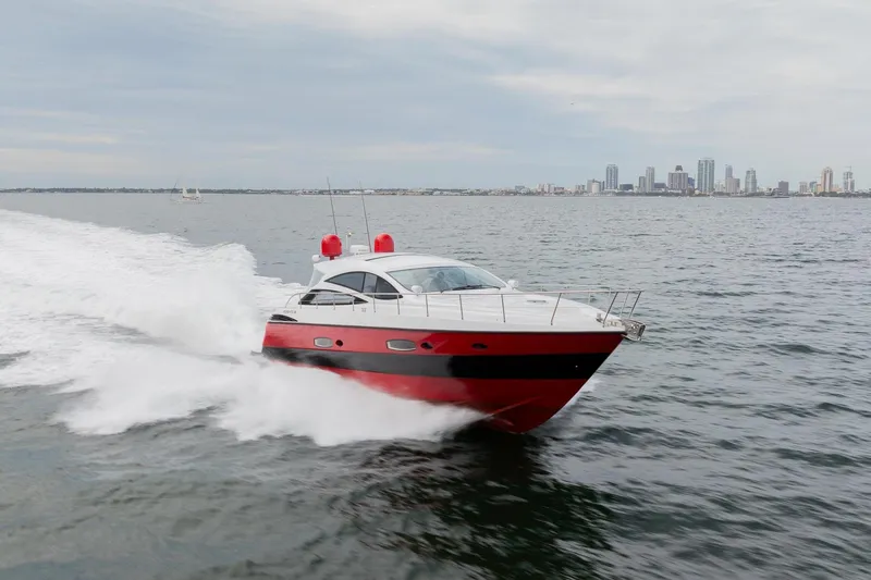 Slide: The Image of Red 2007 Pershing 56 yacht cruising on open water with city skyline in background. - 15