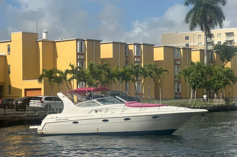 Slide: The Image of 2001 Sea Ray 340 Sundancer yacht cruising near yellow buildings and palm trees. - 16