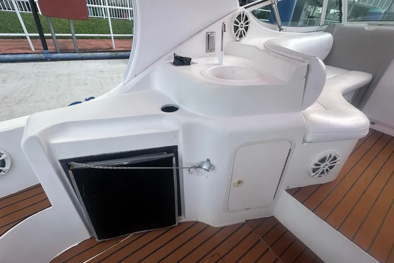 Slide: The Image of 2001 Sea Ray 340 Sundancer cockpit with sink, seating, and storage on teak flooring. - 29