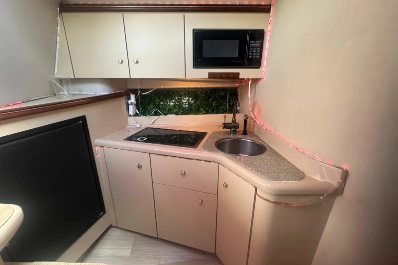 Slide: The Image of 2001 Sea Ray 340 Sundancer kitchen with sink, stove, microwave, and ambient lighting. - 45