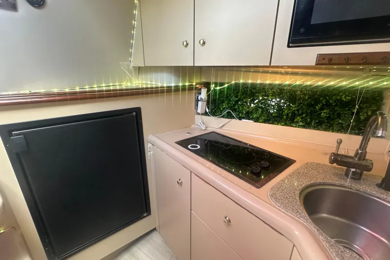 Slide: The Image of 2001 Sea Ray 340 Sundancer kitchen with stove, sink, and ambient lighting. - 46