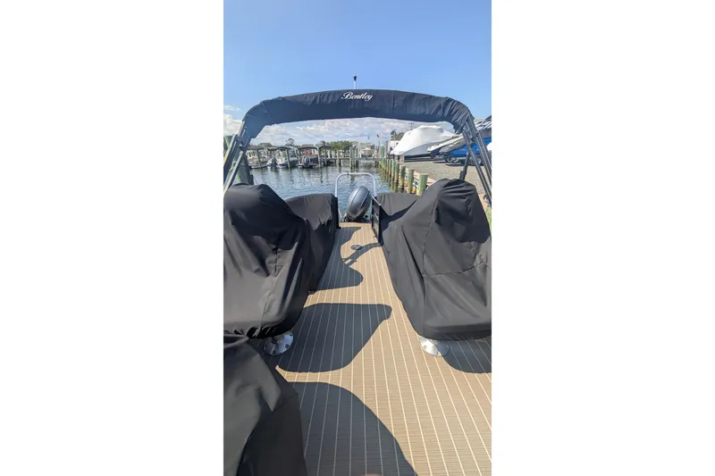 Slide: The Image of 2022 Bentley Pontoons 240 Navigator docked, covered seats, sunny marina view. - 9