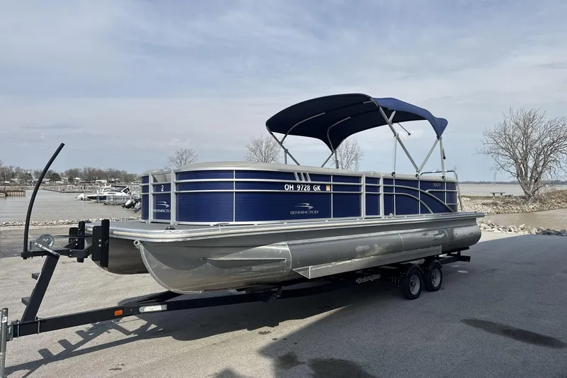 Slide: The Image of 2023 Bennington 25ssrc pontoon boat with blue canopy on trailer by lakeside. - 4