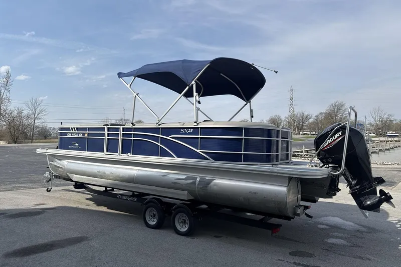 Slide: The Image of 2023 Bennington 25ssrc pontoon boat with blue canopy and Mercury outboard motor. - 6