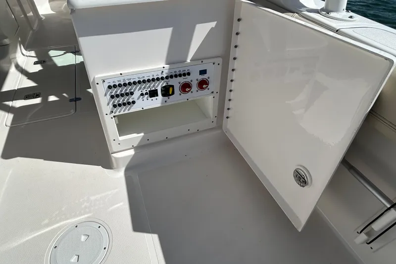 Slide: The Image of 2016 Pursuit DC 265 Dual Console boat electrical panel with open storage compartment. - 12