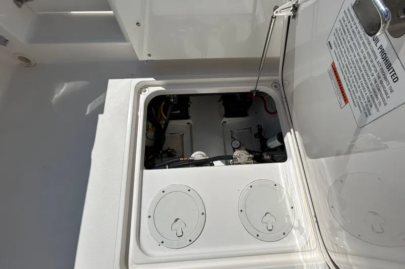 Slide: The Image of 2016 Pursuit DC 265 Dual Console boat storage compartment with open hatch and visible equipment. - 15