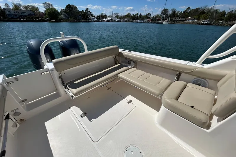 Slide: The Image of 2016 Pursuit DC 265 Dual Console boat interior with beige seating, docked on a sunny day. - 18
