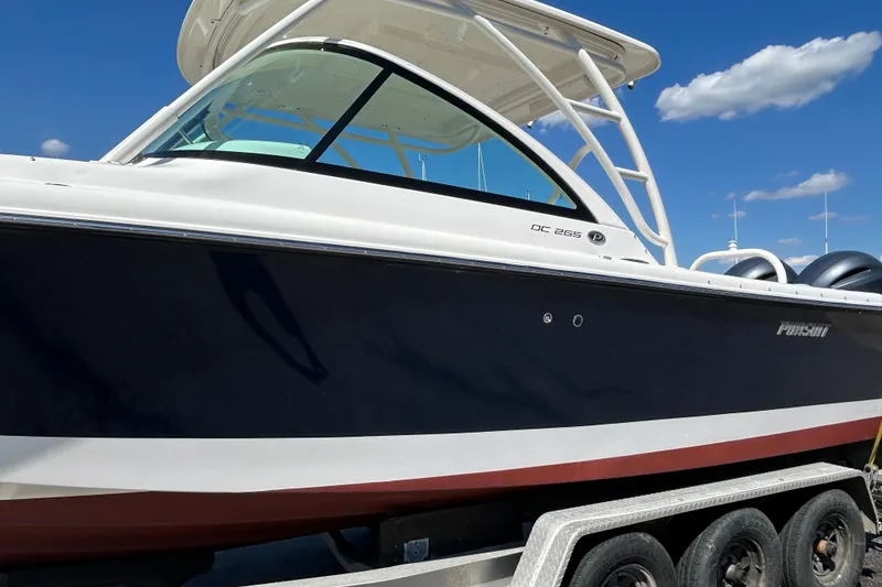 Slide: The Image of 2016 Pursuit DC 265 Dual Console boat on trailer under blue sky. - 2