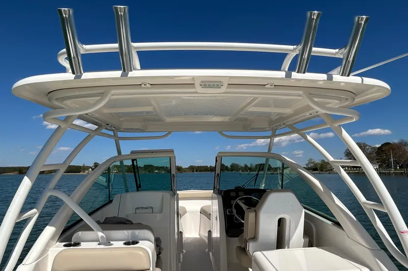 Slide: The Image of 2016 Pursuit DC 265 Dual Console boat interior with seating and helm, under clear blue sky. - 21