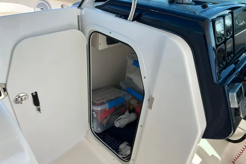 Slide: The Image of Storage compartment on a 2016 Pursuit DC 265 Dual Console boat, containing organized supplies. - 9