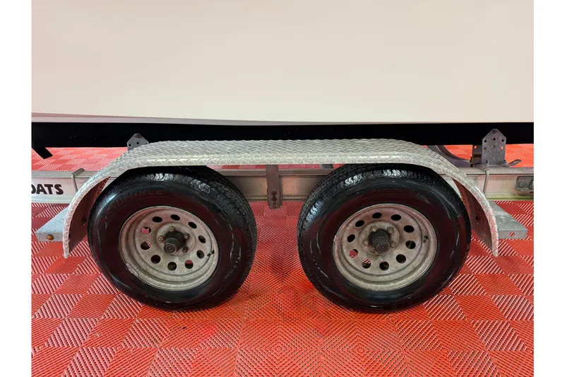 Slide: The Image of Trailer wheels of a 2018 Parker 2100 SE boat on red textured flooring. - 35