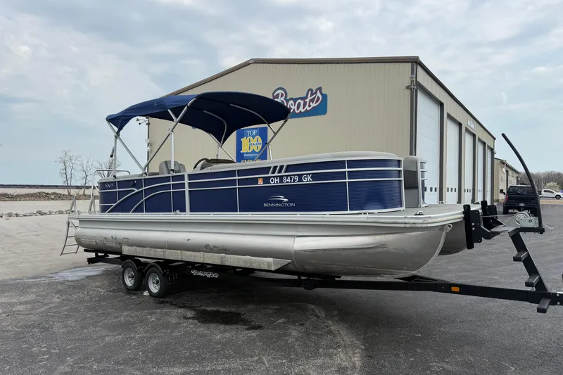 Slide: The Image of 2023 Bennington 25ssrc pontoon boat on trailer, parked outside a boat dealership. - 11