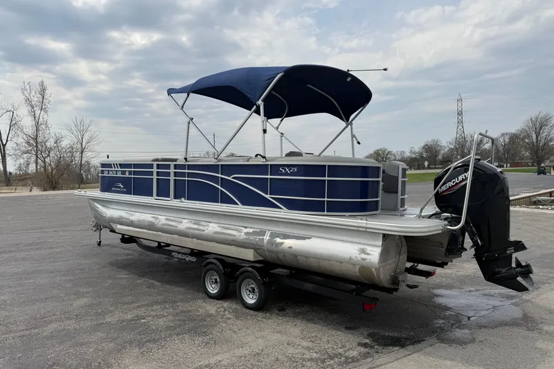 Slide: The Image of 2023 Bennington 25ssrc pontoon boat with blue canopy and Mercury outboard motor. - 13