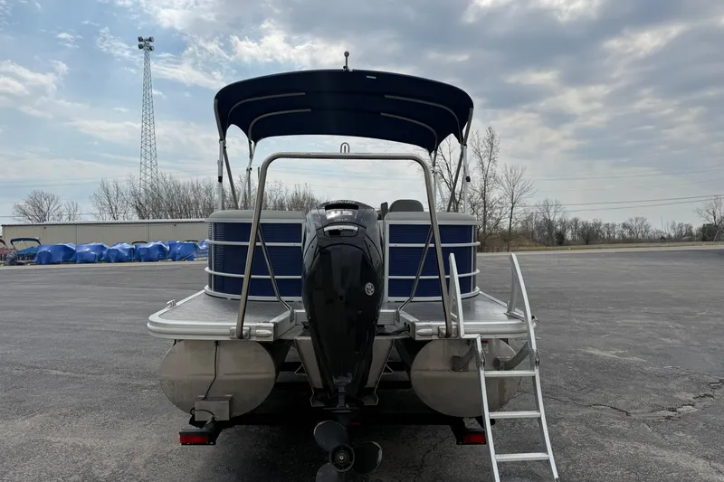 Slide: The Image of 2023 Bennington 25ssrc pontoon boat with canopy and outboard motor, parked on asphalt. - 14