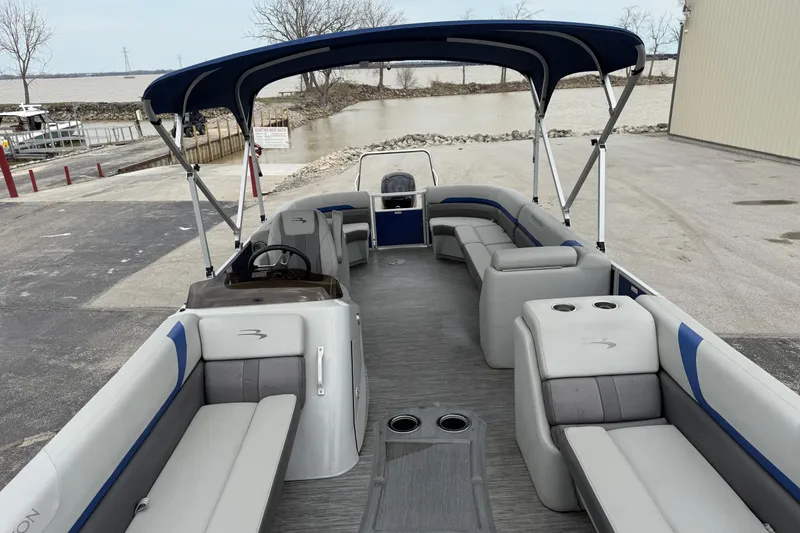 Slide: The Image of 2023 Bennington 25ssrc pontoon boat with spacious seating and canopy at a dockside. - 27