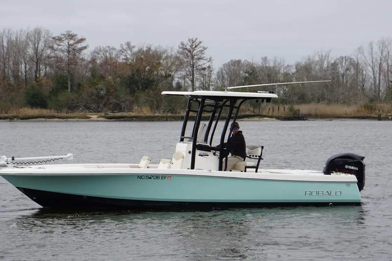The Image of 2017 Robalo 246 Cayman boat on a calm river with trees in the background. - 1