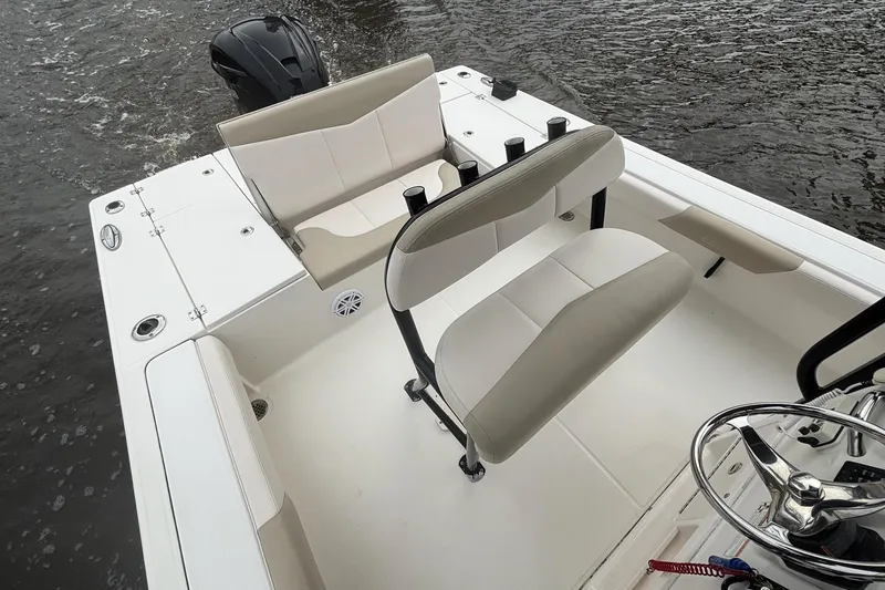 Slide: The Image of 2017 Robalo 246 Cayman boat interior with seating and steering wheel on water. - 14