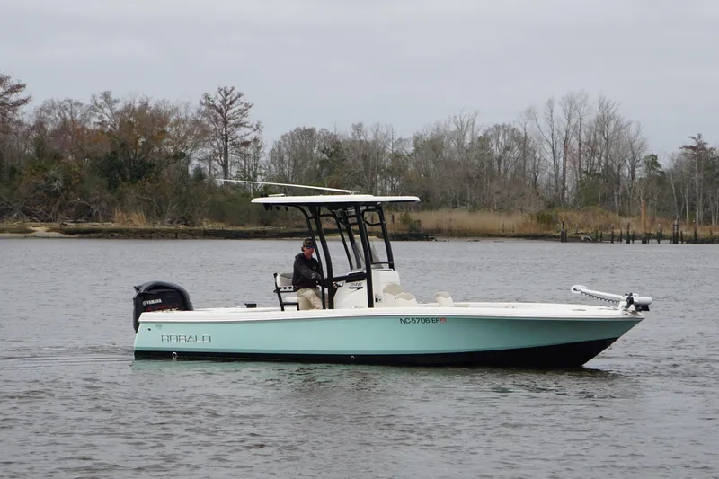 Slide: The Image of 2017 Robalo 246 Cayman boat on calm water with trees in the background. - 17