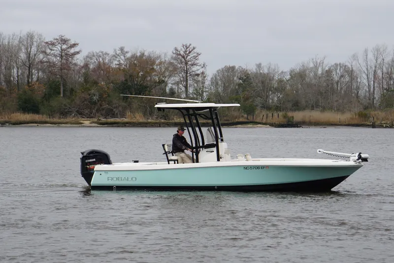 Slide: The Image of 2017 Robalo 246 Cayman boat cruising on a calm river with trees in the background. - 3