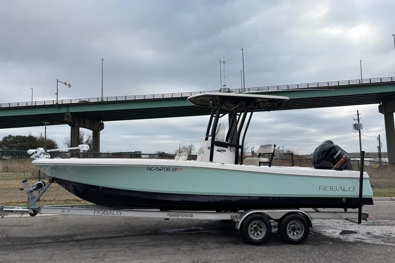 Slide: The Image of 2017 Robalo 246 Cayman boat on trailer under cloudy sky near bridge. - 7