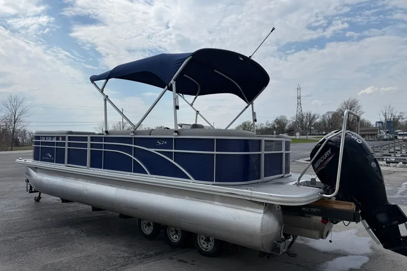 Slide: The Image of 2023 Bennington 24SSRC pontoon boat with blue canopy and Mercury outboard motor. - 14