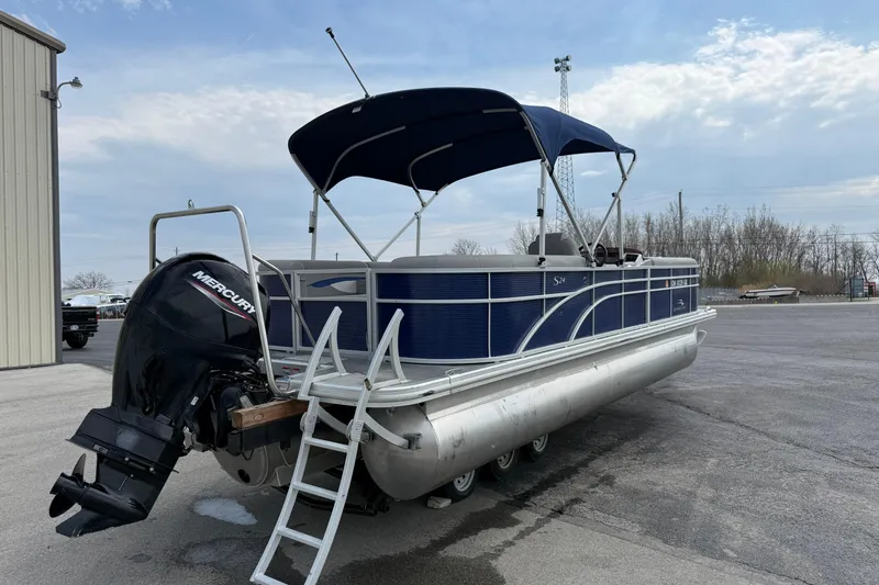 Slide: The Image of 2023 Bennington 24SSRC pontoon boat with Mercury engine and canopy, parked outdoors. - 16