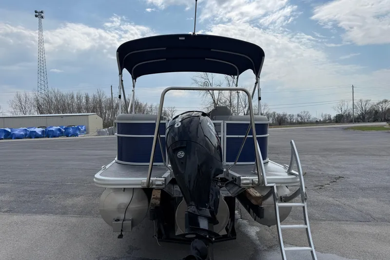 Slide: The Image of 2023 Bennington 24SSRC pontoon boat with canopy and outboard motor, parked on asphalt. - 5