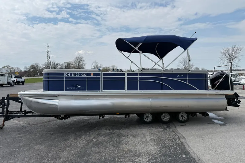 Slide: The Image of 2023 Bennington 24SSRC pontoon boat with blue canopy on a trailer. - 6