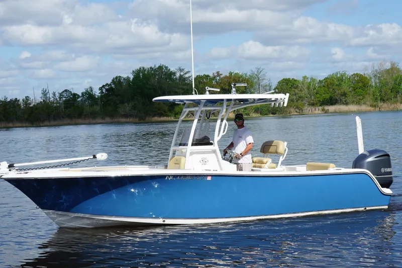 Slide: The Image of 2022 Sportsman Open 242 Center Console boat on calm water, with a person at the helm. - 5