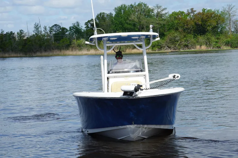 Slide: The Image of 2022 Sportsman Open 242 Center Console boat on calm water, surrounded by trees. - 6