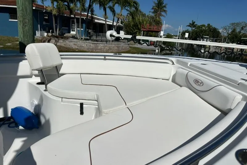 Slide: The Image of 2018 Sea Hunt Ultra 225 boat interior with white seating and coastal background. - 22