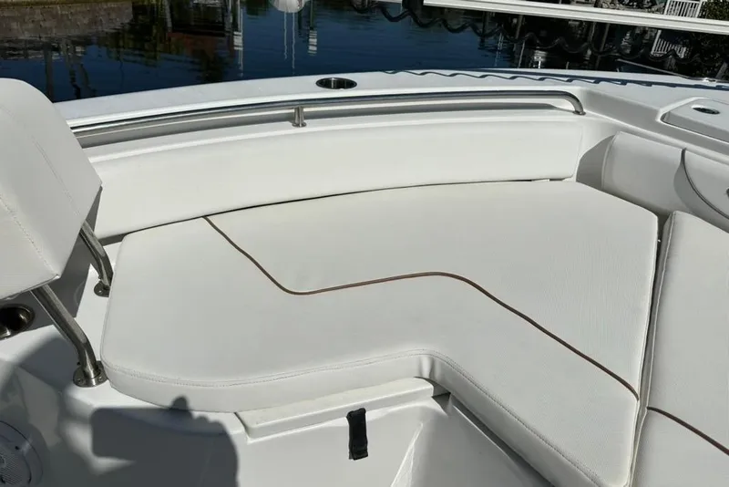 Slide: The Image of 2018 Sea Hunt Ultra 225 boat with white cushioned seating near water. - 25