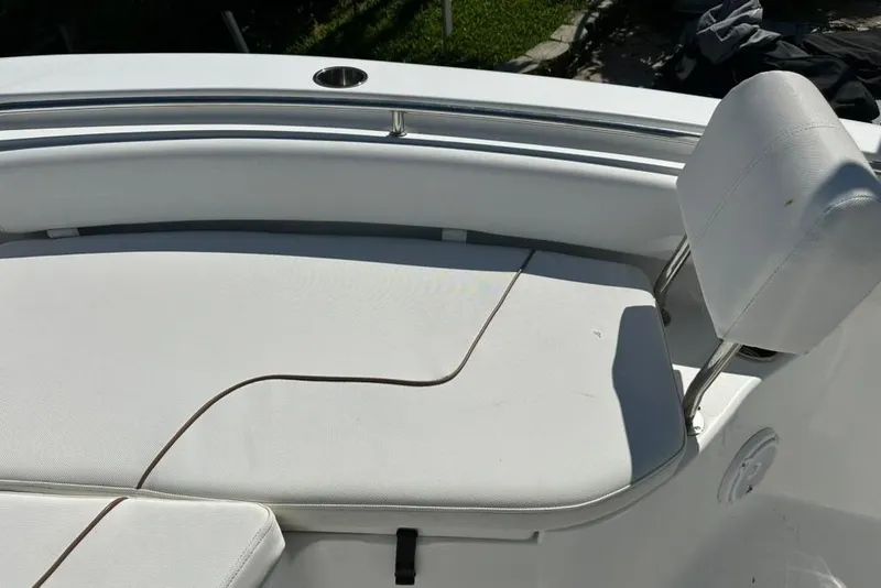 Slide: The Image of 2018 Sea Hunt Ultra 225 boat seating area with white cushioned seats and stainless steel railing. - 28