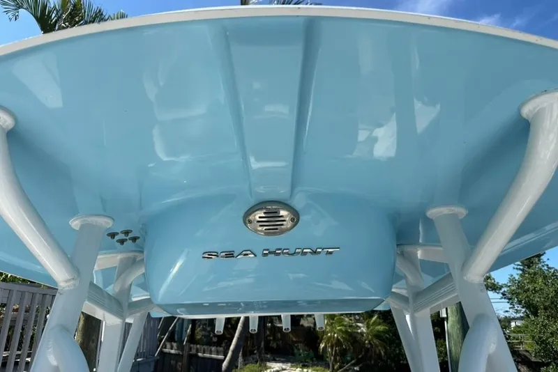 Slide: The Image of 2018 Sea Hunt Ultra 225 boat with blue T-top and white supports. - 36