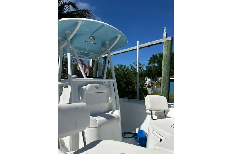 Slide: The Image of 2018 Sea Hunt Ultra 225 boat interior with seating and T-top under clear blue sky. - 38