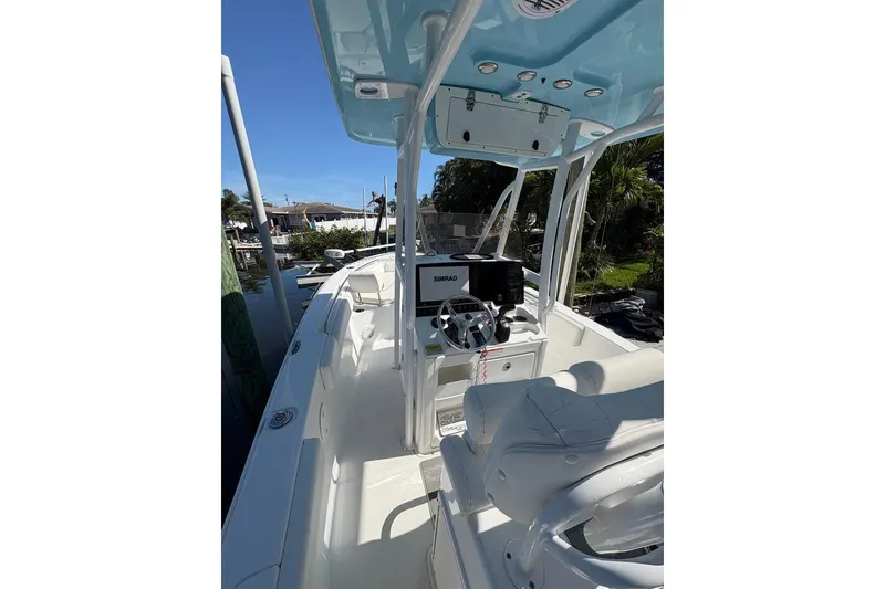 Slide: The Image of 2018 Sea Hunt Ultra 225 boat interior with steering console and seating, docked near water. - 53