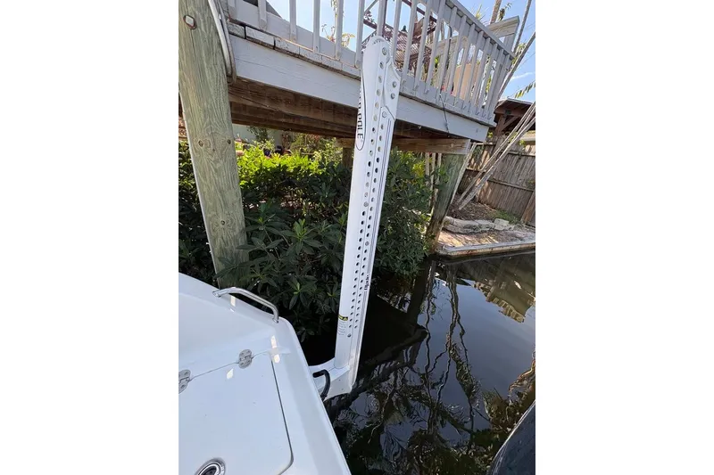 Slide: The Image of 2018 Sea Hunt Ultra 225 boat docked near wooden structure and lush greenery. - 68