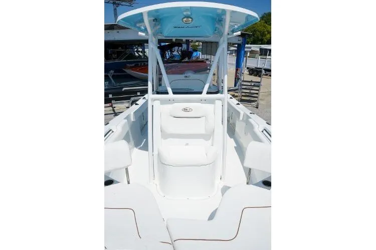Slide: The Image of 2018 Sea Hunt Ultra 225 boat docked by a waterfront home under a clear blue sky. - 7