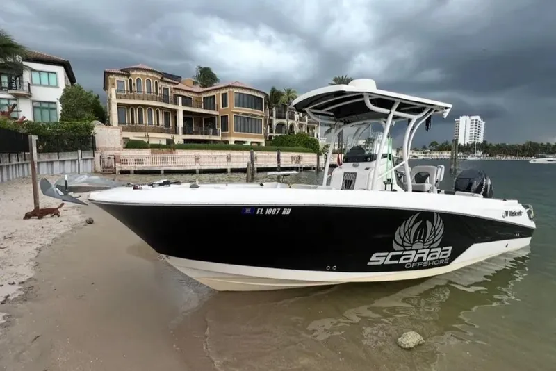 The Image of 2019 Wellcraft 242 Scarab Offshore boat on sandy shore, luxury homes in background. - 0