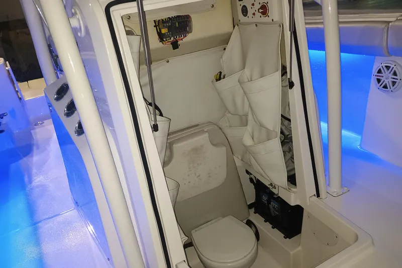 Slide: The Image of 2019 Wellcraft 242 Scarab Offshore boat interior with storage and toilet, illuminated by blue LED lights. - 7